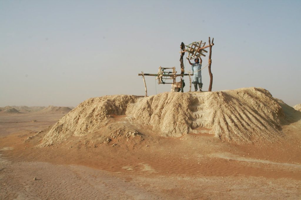 A man working on a traditional mining setup in the arid landscape of Morocco's Draa-Tafilalet.