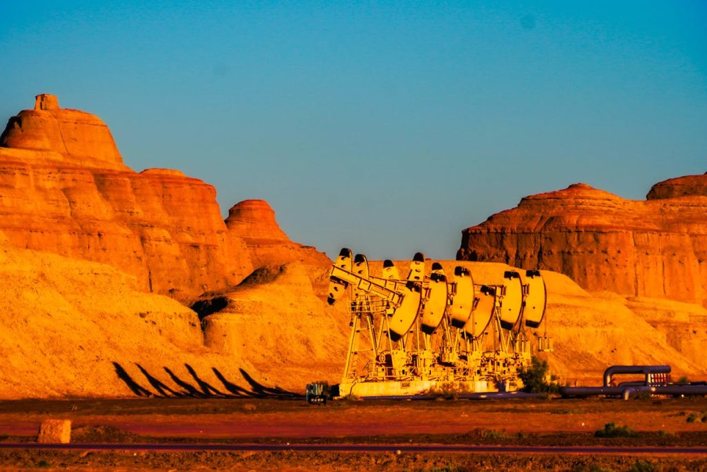 Line of pumpjacks against a stunning rocky landscape at sunset in Karamay, Xinjiang, China.
